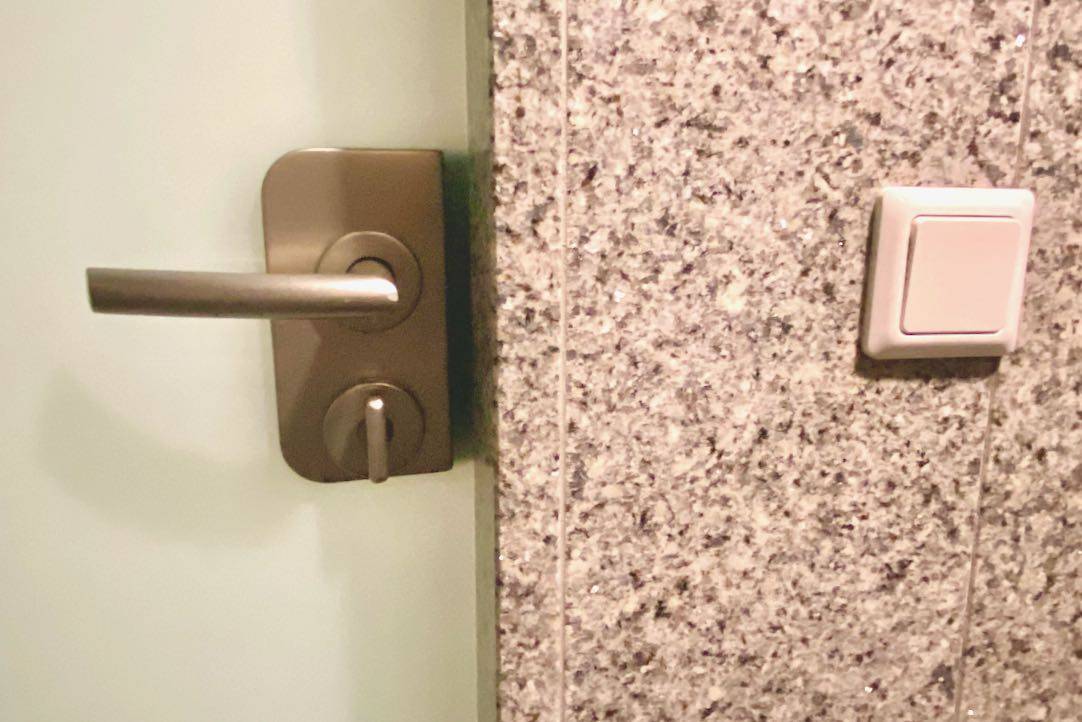 Mecanismo interior de la puerta del aseo PMR de hombres