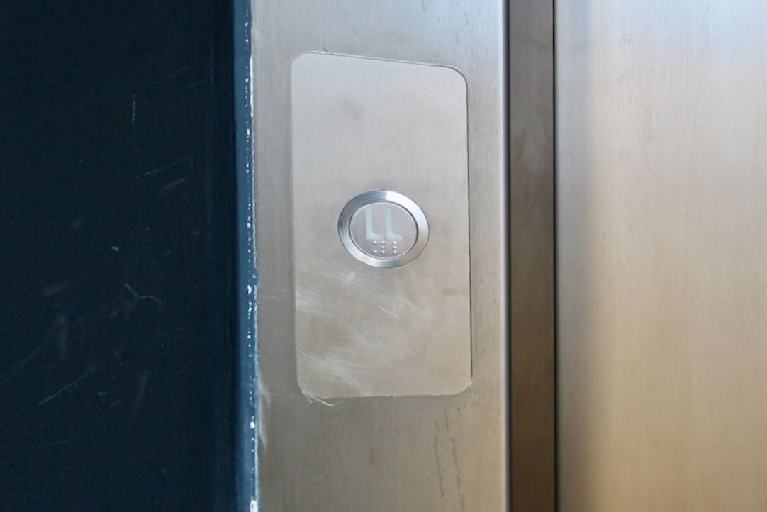 Ascensor de acceso al Ágora. Botón de llamada en planta